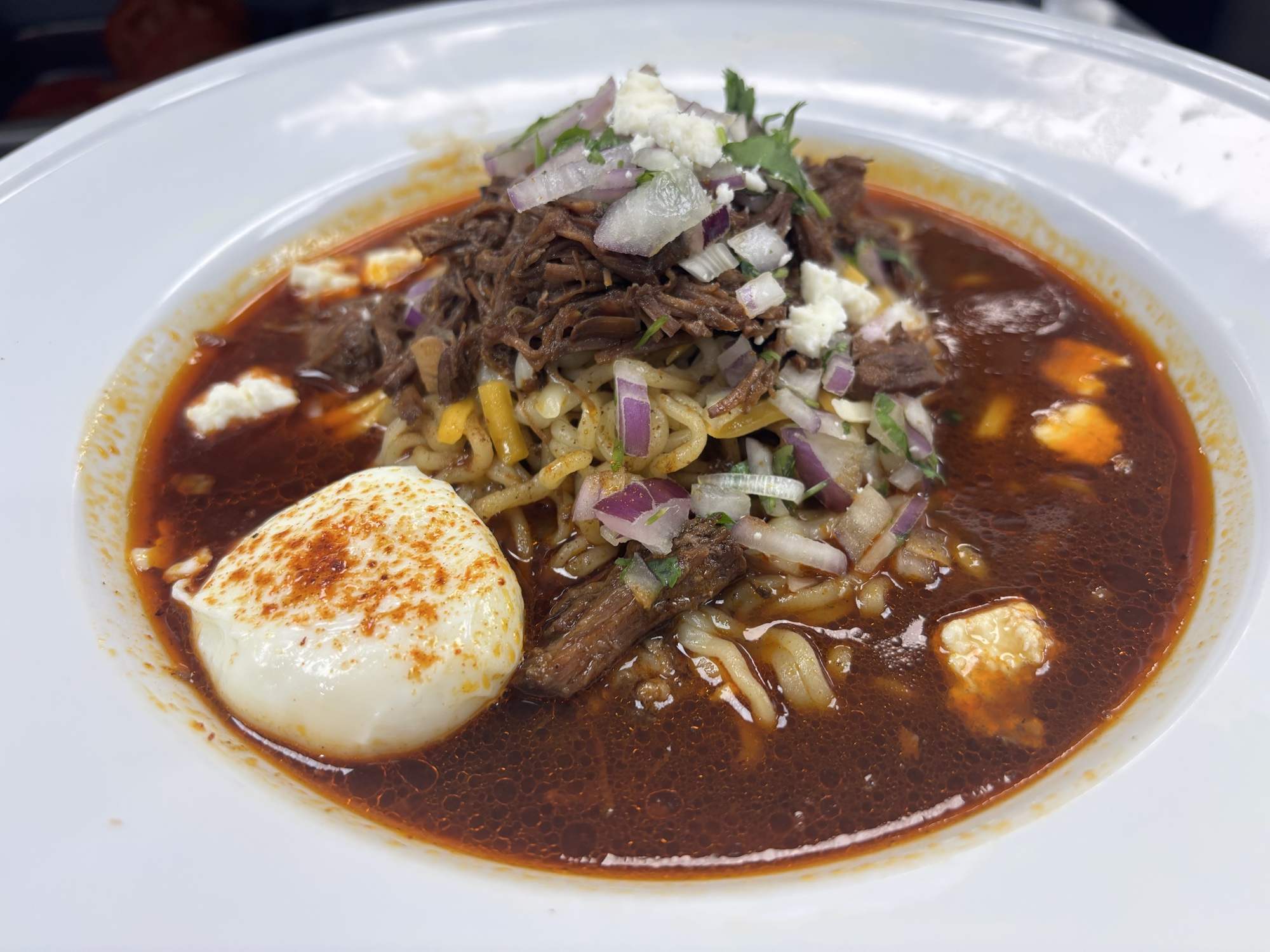 Birria Ramen with slow-braised beef birria in consomé, red onion, cilantro and queso fresco, today's $14 Chef's Choice at Guat-A-Taco in Manning, SC